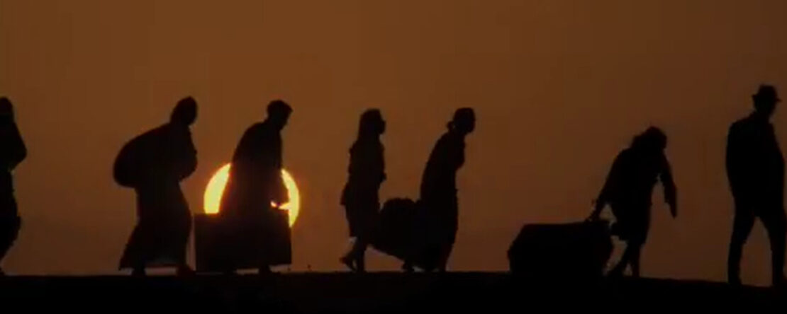Siluetas de personas caminando cargadas con equipaje, con el sol de fondo.