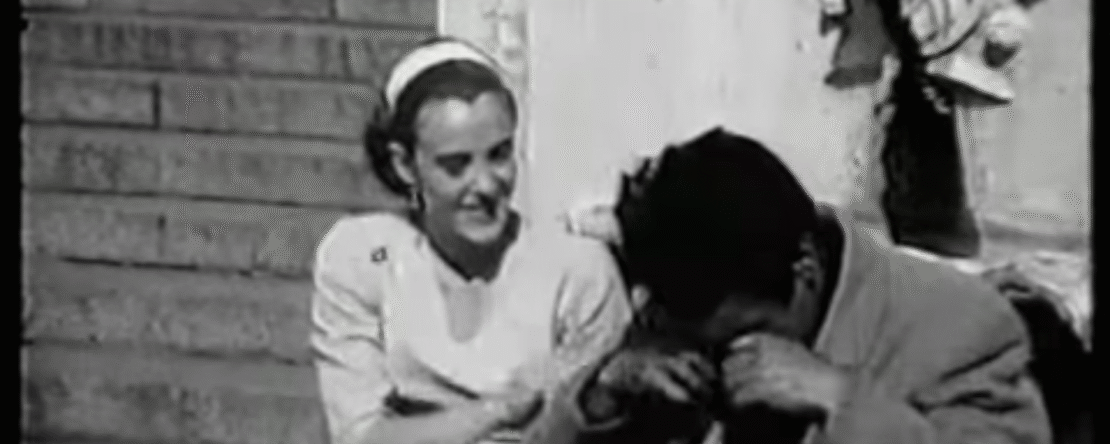 Hombre y mujer sentados en una escalera conversando en una imagen en blanco y negro con subtítulos en portugués.