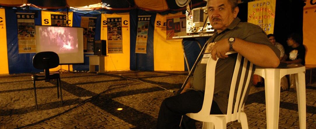 Hombre viendo una película proyectada en una carpa en un evento al aire libre.