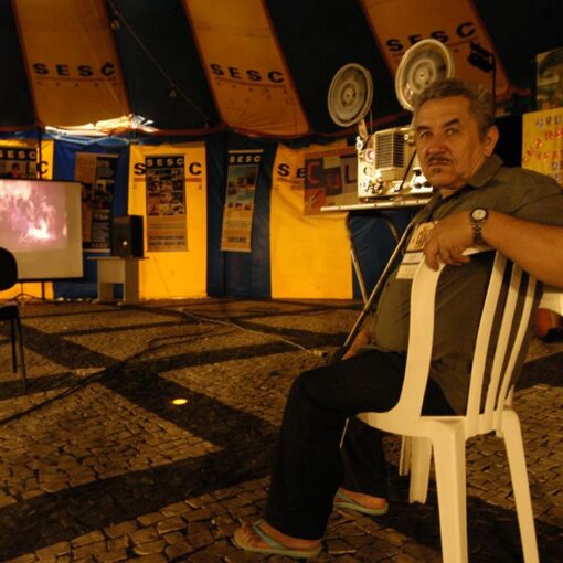 Hombre viendo una película proyectada en una carpa en un evento al aire libre.