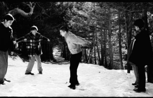 Huellas en la nieve. Fotograma de la película. La imagen en blanco y negro muestra a cuatro personas jóvenes en un bosque nevado.