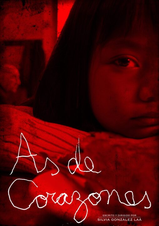 Niña pequeña apoyada sobre la mesa con los brazos cruzados mirando a cámara. Sacada de una escena de As de corazones.