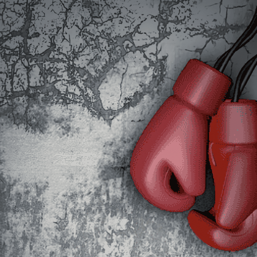 Guantes de boxeo rojos colgados frente a una pared gris agrietada.