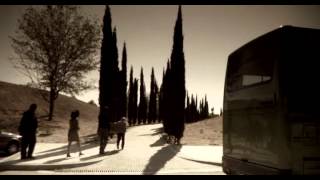 el útlimo adiós Fotograma de El último adiós. Paisaje del pueblo. Personas vestidas de negro y cabizbajas caminan entre árboles.
