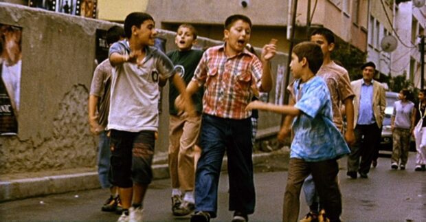 Fotograma sacado del corto Es mi turno en la que muestra un grupo de niños , en la calle, hablando entre ellos en dirección a algún lugar.