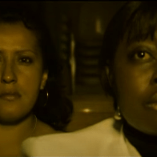 Una mujer negra y una mujer blanca, ambas observando al frente con expresión seria. La imagen refleja una mirada de determinación y reflexión.