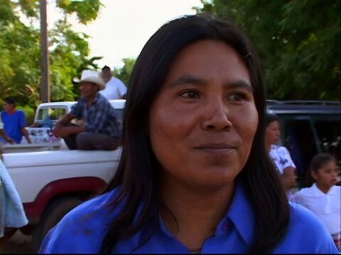 Una de las participantes del documental siendo entrevistada. Viste un polo azul eléctrico. Tiene piel morena, pelo negro largo.