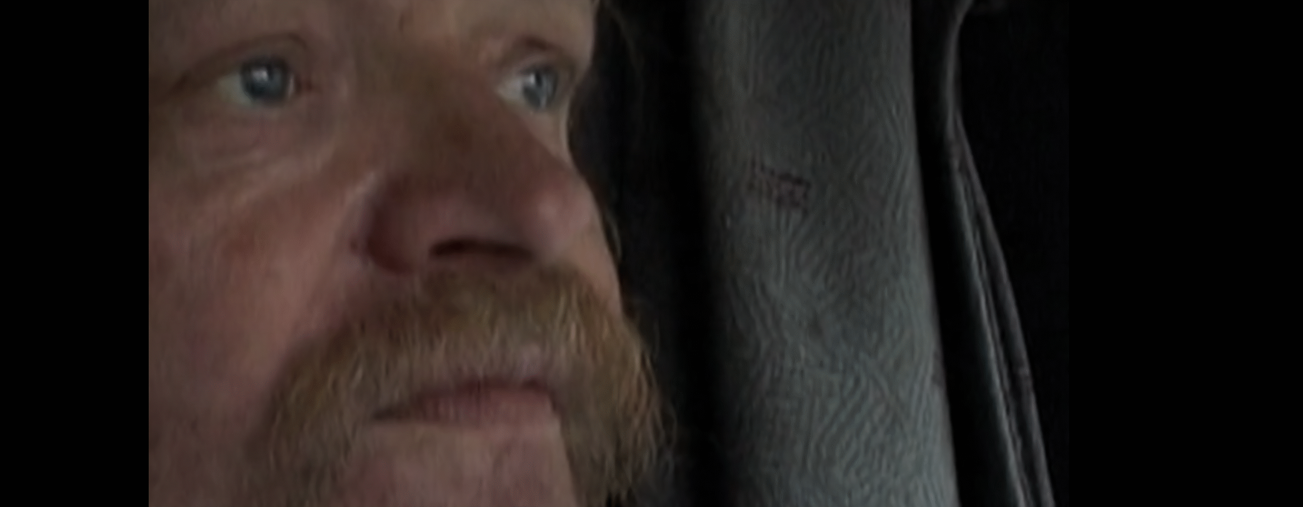 Primer plano del rostro de Bertil, un camionero de mediana edad con bigote y mirada fija, observado en silencio mientras conduce, reflejando introspección y el paso del tiempo durante sus largas horas en la carretera.