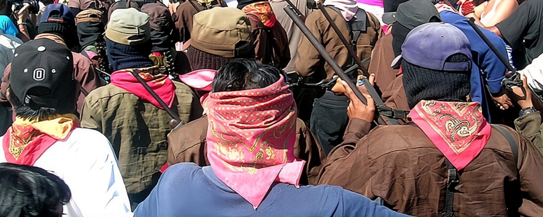 Activistas pertenecientes a la Otra Campaña manifestandose. Algunos se encuentran armados y con la cara cubierta con un pasamontañas y pañuelos.