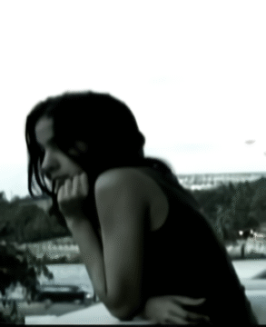 Joven apoyada sobre una barandilla mirando al horizonte en una imagen en blanco y negro.