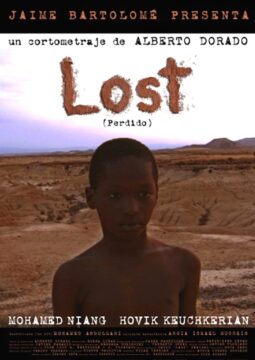 Cartel del cortometraje Lost (Perdido). En el centro, un niño de mirada seria aparece de pie, sin camisa, en un paisaje árido y desértico.