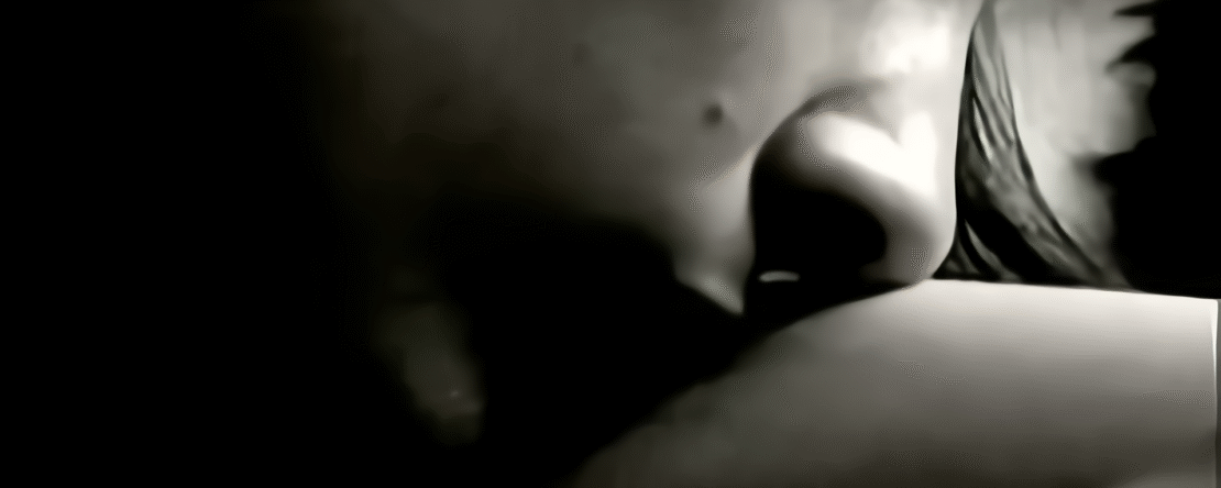 Primer plano del rostro de una persona acercándose suavemente a otro cuerpo en una imagen en blanco y negro.