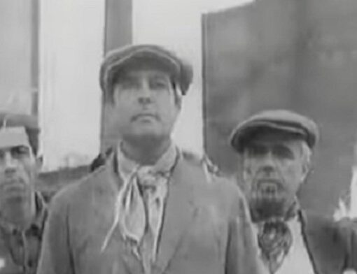 Un hombre, en primer plano mirando al frente, y detrás, otros dos. Imagen en blanco y negro.