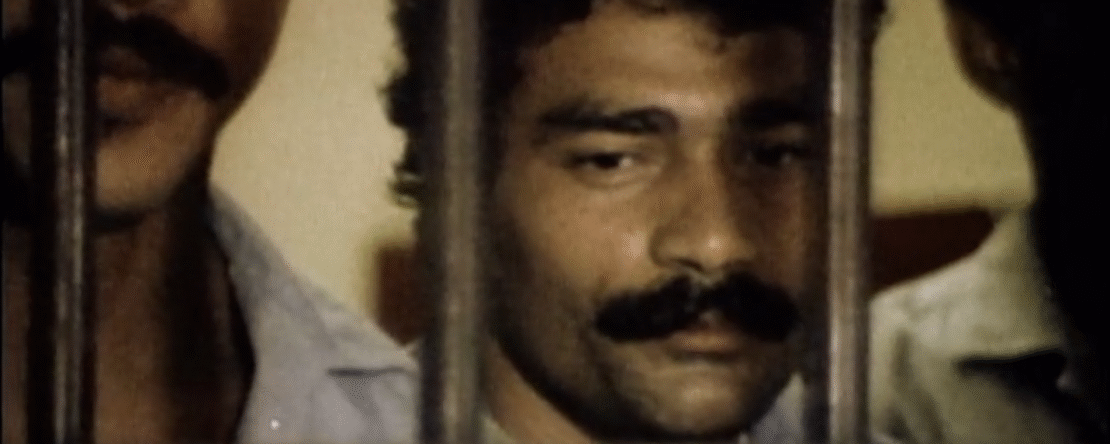 Fragmento del documental - Hombre con bigote y cara triste tras las rejas rodeado de otros dos individuos