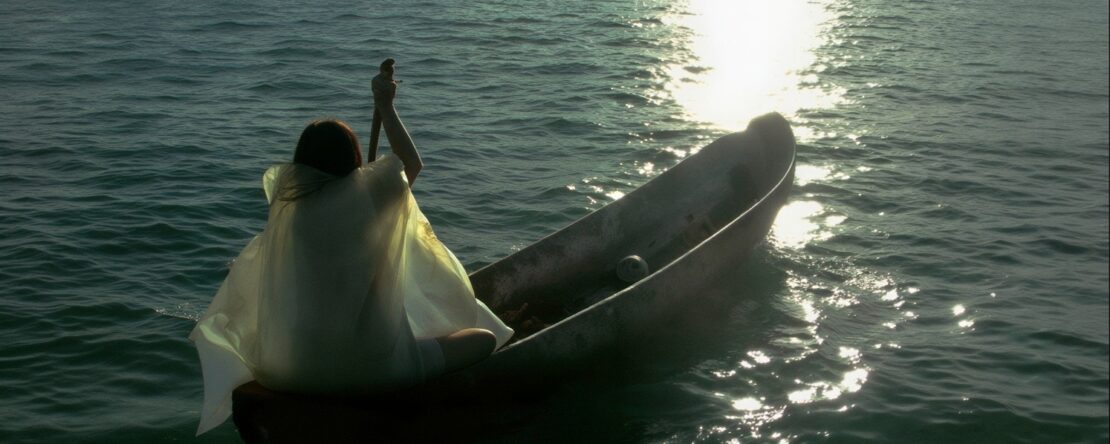 Imagen de Marina, la esposa del pescador remando en el mar en su pequeño bote hacia el horizonte bajo el sol del atardecer