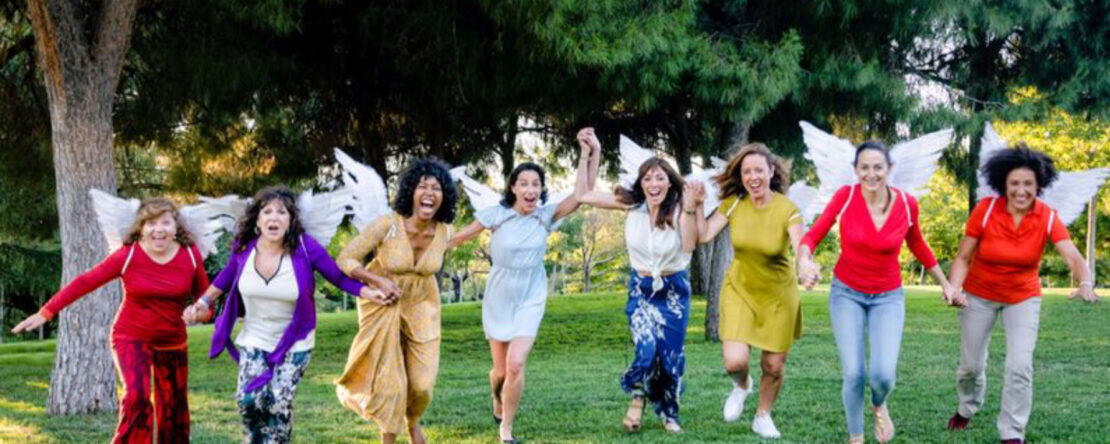 Fotograma de "Ángeles Rotos". Fila de mujeres con alas de ángeles corren alegres hacia cámara en un parque.
