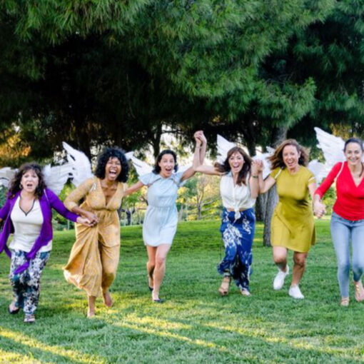 Fotograma de "Ángeles Rotos". Fila de mujeres con alas de ángeles corren alegres hacia cámara en un parque.