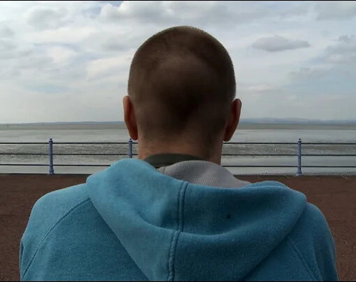Imagen de un joven sentado mirando al mar