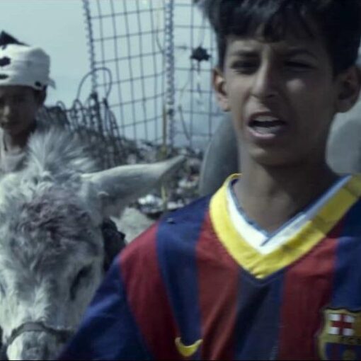 Fotograma de Cierra bien tus ojos en el que aparece un niño vestido con una camiseta del Barça. Al fondo, hay otro niño montado en el burro.