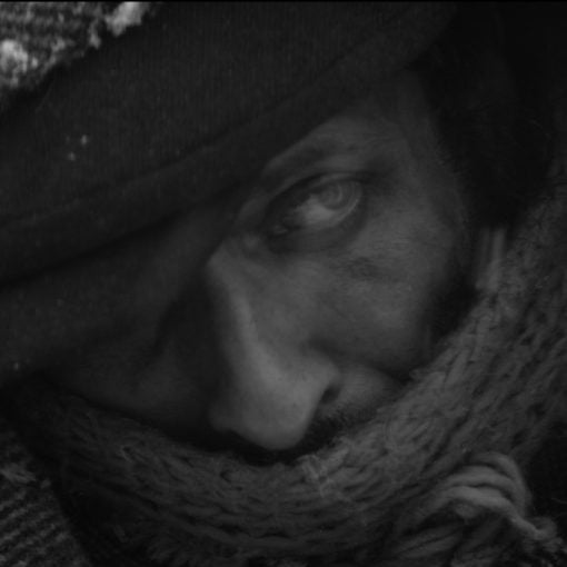 "Un hombre aparece en una fotografía en blanco y negro. Su expresión es seria y su mirada intensa, transmitiendo una sensación de profundidad y contemplación