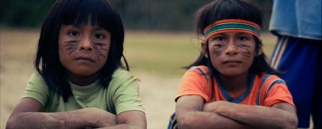 Dos niños nativos americanos nos miran fijamente, con una expresión serena y profunda que transmite calma y dignidad. Sus rostros, enmarcados por la luz natural.