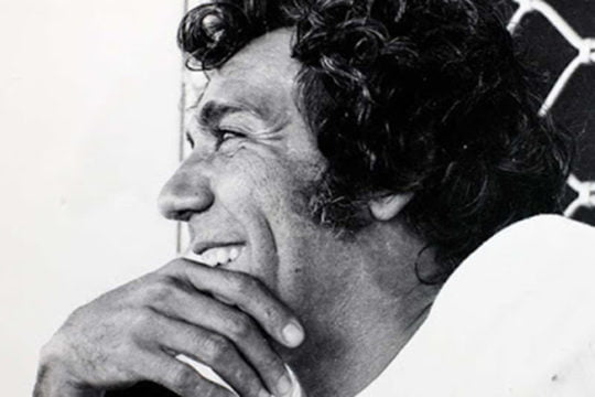 Fotografía lateral de Álvaro Cepeda Samudio mientras ríe, apoyando su mano en la barbilla.