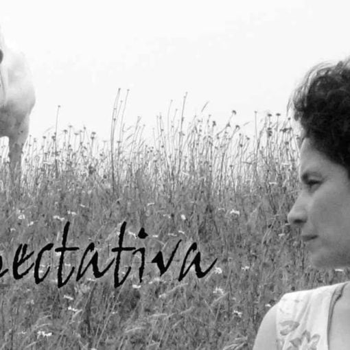 Fotograma en blanco y negro del cortometraje Xpectativa, donde un hombre camina solo por un pasillo desierto, con expresión seria y ambiente sombrío, reflejando el tono introspectivo de la historia.