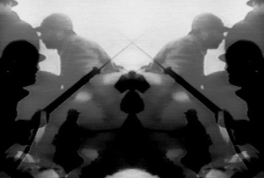 Fotograma en blanco y negro del cortometraje +30 -29, mostrando dos soldados en repetición visual.