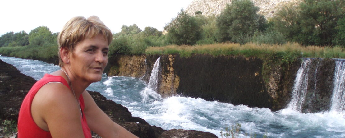 Fotograma de "No olvidar, voces más allá del olvido". Una mujer sonríe delante de una cascada.