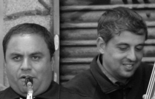 Grupo de hombres, con gesto alegre, tocando instrumentos en la calle. Foto en blanco y negro.