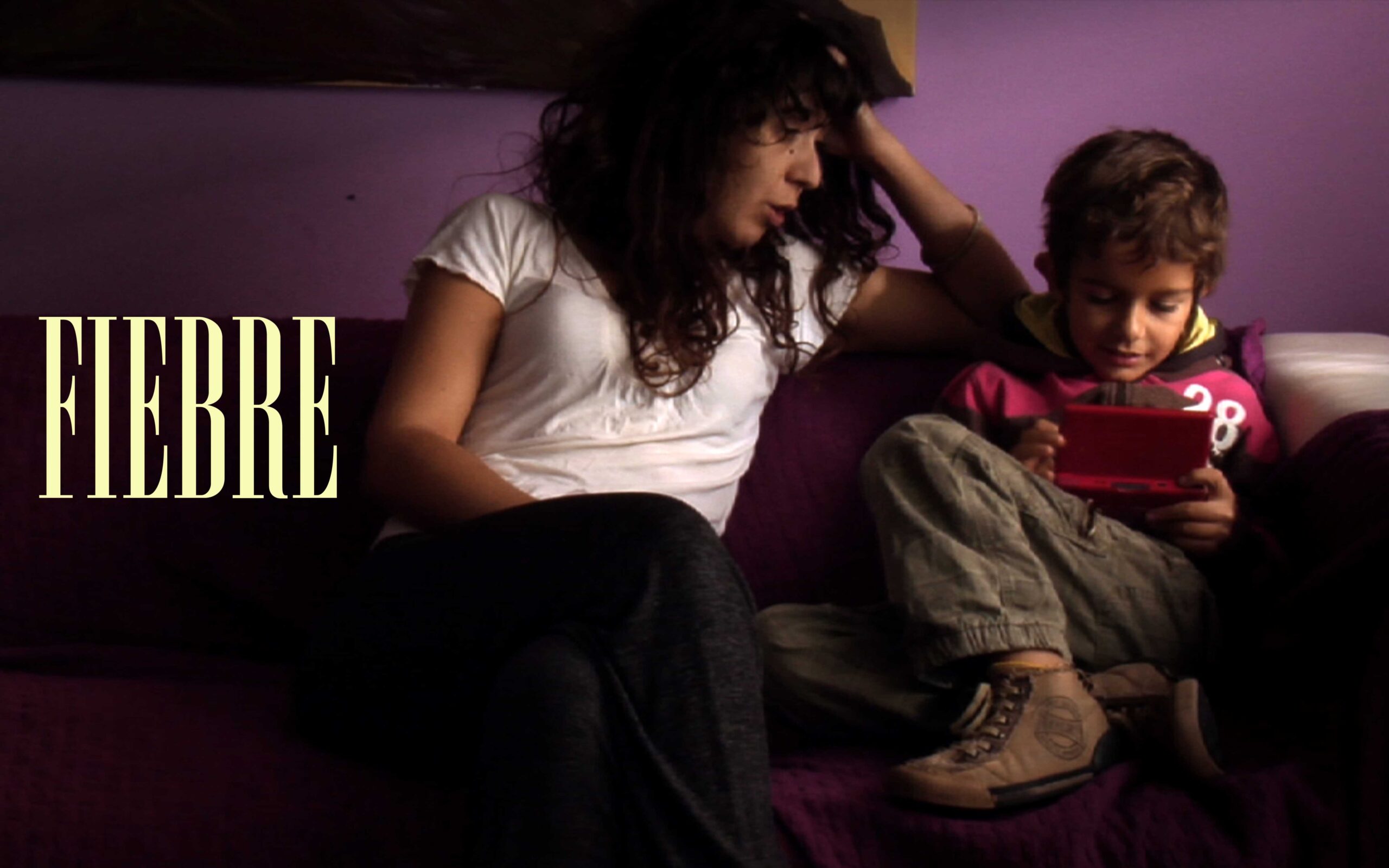 Como carátula de presentación, esto fotograma con el rótulo de Fiebre en la composición presenta a madre e hijo sentados en el sofá. Olaia trata de interactuar con Nico mientras este está concentrado jugando a la consola.