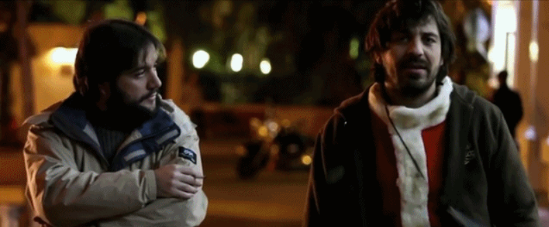 Fotograma de En mal estado en el que aparecen dos hombres caminando por la calle de noche y hablando entre ellos.