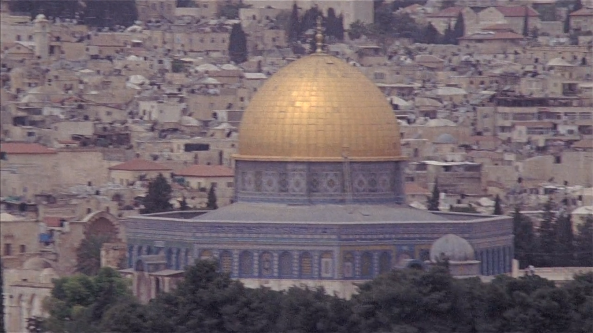 Vista panorámica de la Cúpula de la Roca en Jerusalén con su cúpula dorada, rodeada por edificaciones históricas de la ciudad.