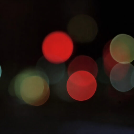 Luces de la ciudad desenfocadas sobre un plano negro, recuerdan a las luciérnagas en la noche.