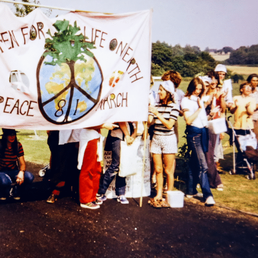 Grupo de personas participando en una manifestación con una pancarta que muestra un símbolo de paz y el mensaje sobre la marcha por la vida y la paz.