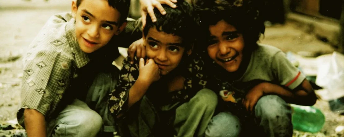 Fotograma en el que aparecen tres niños agachados abrazados.