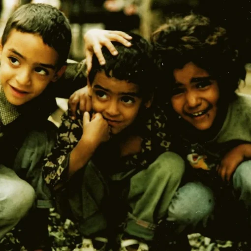 Fotograma en el que aparecen tres niños agachados abrazados.