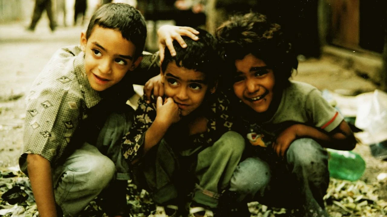 Fotograma en el que aparecen tres niños agachados abrazados.