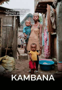 Imagen de una madre con sus dos hijos. se encuentran en un pueblo muy humilde, las casas están hechas de madera y el suelo es barro.