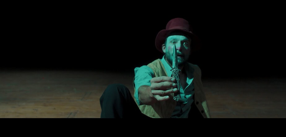 Esta imagen ilustra uno de los momentos más intensos del cortometraje El Petirrojo, en el que se evidencia la amenaza y la violencia ejercida por el personaje del payaso. Su expresión y el gesto de mostrar el cuchillo simbolizan la tensión emocional y física que atraviesa la protagonista. La escena, ambientada en el espacio teatral del circo, refuerza visualmente la temática central del filme: la lucha contra el abuso en entornos donde la apariencia de espectáculo oculta conflictos personales profundos. Su inclusión en la entrada busca subrayar la dimensión simbólica del circo como escenario de opresión y resistencia.