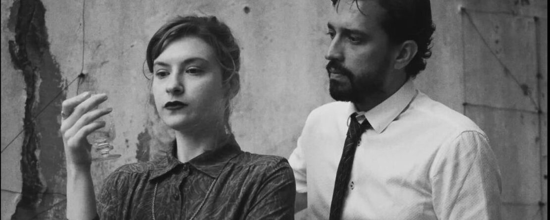 Un hombre y una mujer en blanco y negro, con la mujer sosteniendo un objeto translúcido.