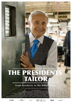 Cartel del documental biográfico, El sastre de los presidentes, donde el protagonista Martín Greenfield aparece sonriente abriéndonos la puerta de su taller invitándonos a entrar. Vestido muy elegante con camisa blanca, chaleco y pantalón grises a jugo parte de un traje y corbata azul.