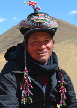 Fotografía 3/4 del director Rómulo Sulca en el rodaje de Érase una vez en los Andes vestido con un abrigo negro y un gorro de ropa regional peruana sobre su gorra.