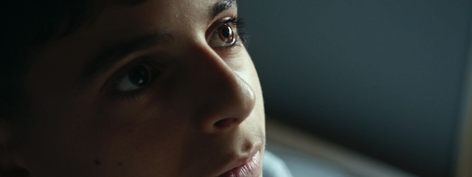 Primer plano del rostro de un joven. Mirada pensativa hacia arriba.