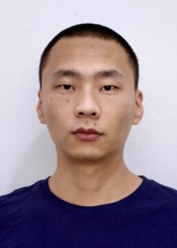Fotografía tipo carnet del director del documental República, Jin Jiang con una camiseta azul marino y un fondo blanco.