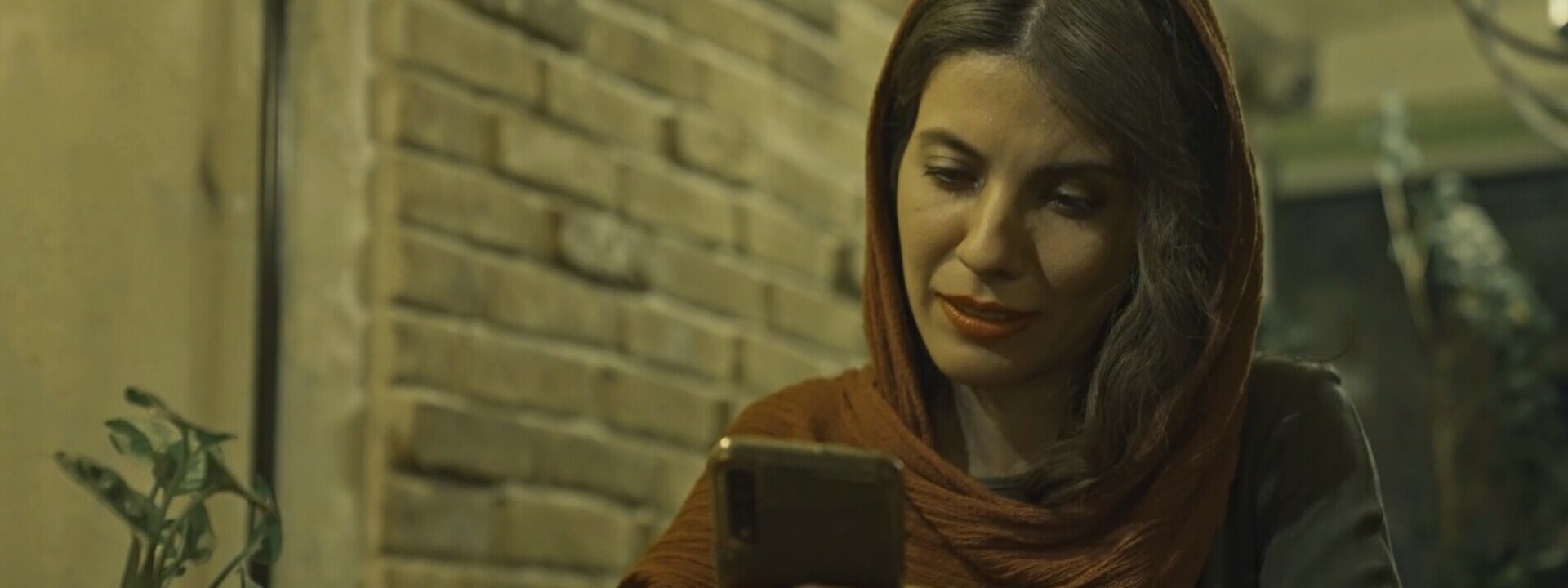 Mujer con pañuelo en la cabeza sentada mirando el movil.