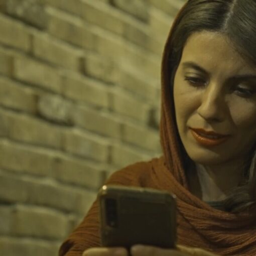 Mujer con pañuelo en la cabeza sentada mirando el movil.