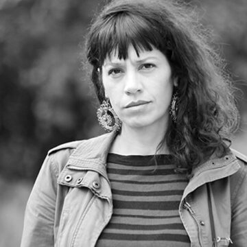 Fotografía en blanco y negro de Belén Revollo, cineasta y docente argentina, nacida en San Salvador de Jujuy. Reconocida por su obra que visibiliza las realidades de las mujeres rurales del noroeste argentino, como se ve en su documental "Wacay, mujeres del tabacal", que retrata la vida y lucha de trabajadoras tabacaleras y ha sido premiado en festivales internacionales. Con su cine, Belén Revollo busca dar voz a quienes históricamente fueron silenciadas.