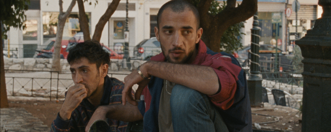 Fotograma de Hacia una tierra desconocida en el que aparecen dos hombres sentados en un banco en la calle.