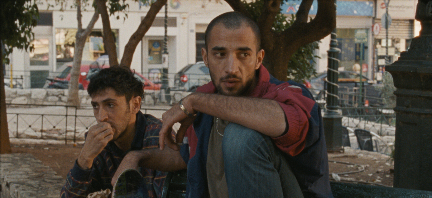 Fotograma de Hacia una tierra desconocida en el que aparecen dos hombres sentados en un banco en la calle.